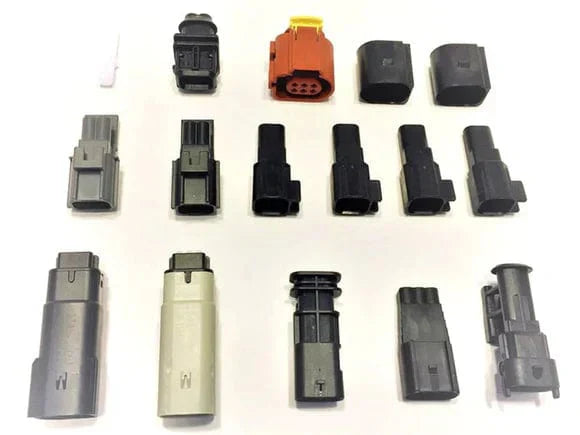 Assorted gray, black and orange harness connector plugs laid out in rows